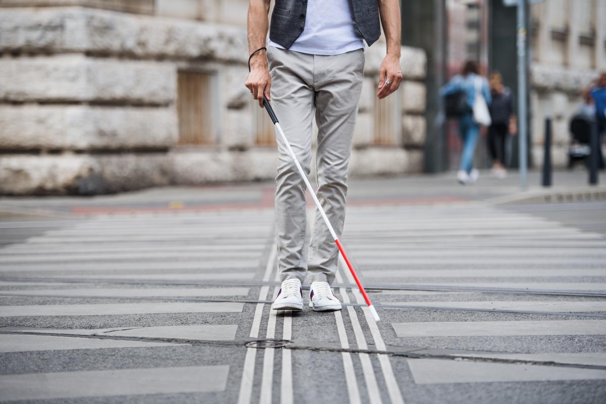 Homme traversant un passage piéton avec une canne blanche