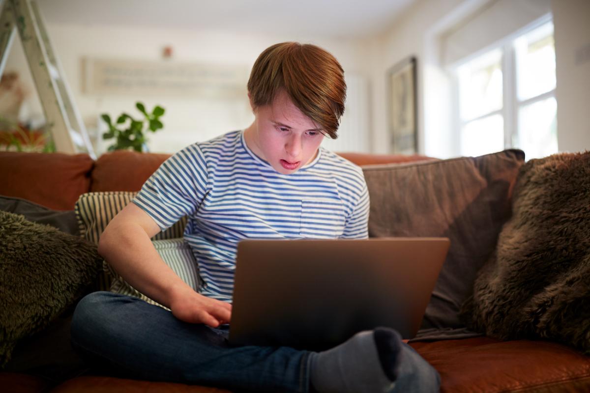 Jeune homme atteint de trisomie devant son ordinateur
